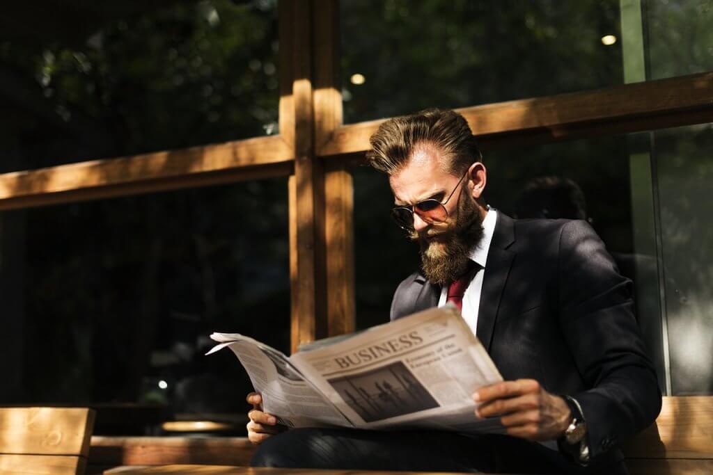 Businessman reading a newspaper about the best beard trimmer 